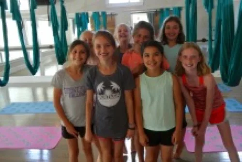 Group of girls smiling together at a Studio143 birthday party with aerial silks in the background