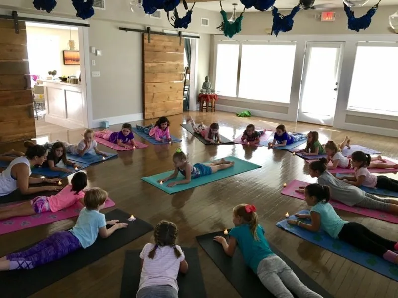 Children practicing yoga on mats inside the Studio143 studio with aerial silks overhead